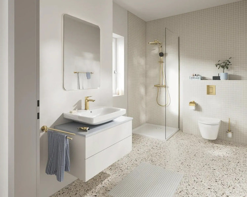 Moderne, lichte badkamer met wit wastafelmeubel, gouden kranen, een inloopdouche en terrazzovloer.