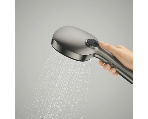 Een hand houdt een handdouche vast waar water uit spuit, met een ronde selectieknop op de achterkant.