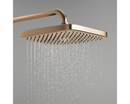 Rechthoekige regendouche in koperlook met stromend water uit de sproeiers.