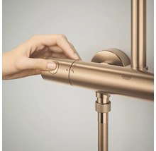 Een hand bedient de draaiknop van een Grohe douchekraan met thermostaat.