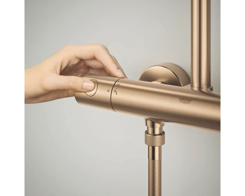 Een hand bedient de draaiknop van een Grohe douchekraan met thermostaat.