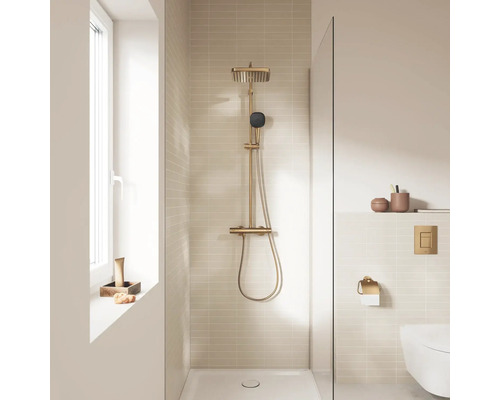 Moderne badkamer met een goudkleurig douchesysteem, stortdouche en beige tegels in een inloopdouche.