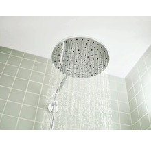 Ronde hoofddouche met stromend water voor een betegelde wand.