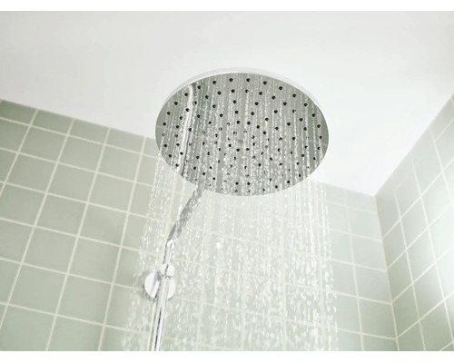 Ronde hoofddouche met stromend water voor een betegelde wand.