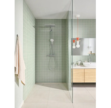 Moderne badkamer met inloopdouche, lichtgroene tegels, chromen douchesysteem, glazen wand en houten wastafelmeubel.