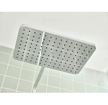 Rechthoekige hoofddouche met sproeigaatjes en Grohe Logo, gemonteerd aan de muur in een badkamer.