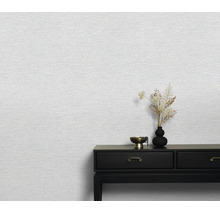 Gestructureerd vliesbehang op een muur met een donkere sidetable en vaas ter decoratie in een minimalistische woonruimte.