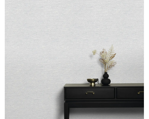 Gestructureerd vliesbehang op een muur met een donkere sidetable en vaas ter decoratie in een minimalistische woonruimte.