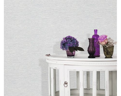 Getextureerd vliesbehang in lichte tinten voor een ronde bijzettafel met bloemendecoratie en vazen.