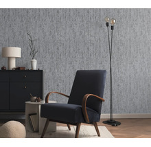 Woonkamer met vliesbehang in betonlook, fauteuil, dressoir en vloerlamp in een moderne interieurstijl.