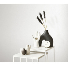 Decoratieve objecten op een witte marmeren tafel met klok, vazen in de vorm van een hand en abstracte vorm, en gedroogde bloemen.