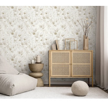 Vliesbehang met floraal bladerpatroon in een lichte woonkamer ingericht met een rotan kast en woonaccessoires.