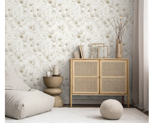 Vliesbehang met floraal bladerpatroon in een lichte woonkamer ingericht met een rotan kast en woonaccessoires.