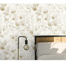 Vliesbehang met botanisch bladerpatroon in een slaapkamer met lamp en bedframe.