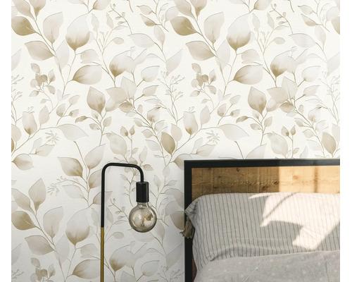Vliesbehang met botanisch bladerpatroon in een slaapkamer met lamp en bedframe.