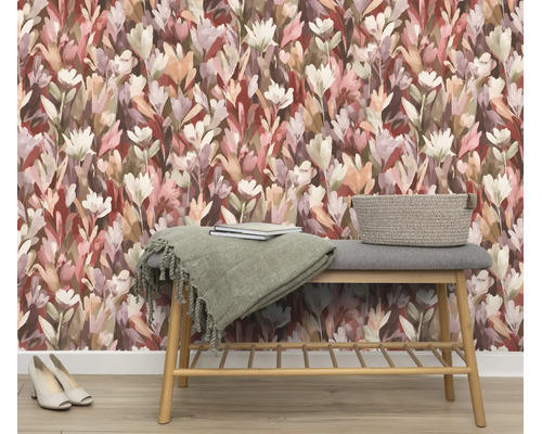 Woonruimte met vliesbehang met bloemenpatroon in aquarellook en een houten bankje met kussens en een mand van vlechtwerk als opbergruimte