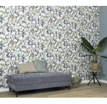 Woonkamer met vliesbehang met bloemenpatroon in aquarel, een gestoffeerde bank en een kamerplant op een bijzettafel.