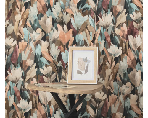Vliesbehang met bloemenpatroon in een schilderkunstige stijl met een kleine fotolijst op een bijzettafel voor de muur.