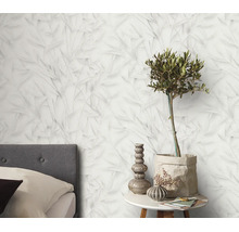 Vliesbehang met een fijn bladerpatroon in een slaapkamer met nachtkastje en decoratieve elementen.