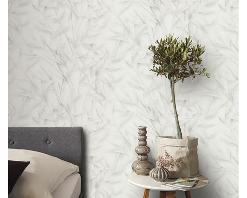 Vliesbehang met een fijn bladerpatroon in een slaapkamer met nachtkastje en decoratieve elementen.
