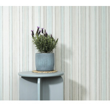 Vliesbehang met verticaal streeppatroon tegen een muur met plant in een bloempot op een ronde bijzettafel.