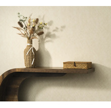 Houten wandconsole met een gevlochten vaas met droogbloemen en een gevlochten opbergdoos tegen een behang met structuur.