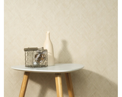 Gestructureerd behang met een fijn patroon geplaatst voor een muur met een kleine bijzettafel een vaas en een decoratief object in een draadmand.