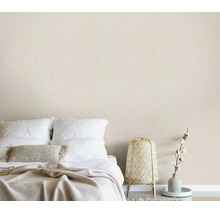 Een minimalistische slaapkamer met gestructureerd behang, een opgemaakt bed en een decoratieve rotan lamp in een natuurlijk design.