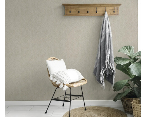 Woonkamer met gestructureerd vliesbehang, een rotan stoel met kussens, een houten kapstok en een kamerplant in een natuurlijke stijl.