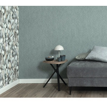 Woonkamer met vliesbehang, een muur met bloemenpatroon en een muur met textieloptiek, naast een bijzettafel en een gestoffeerde bank.