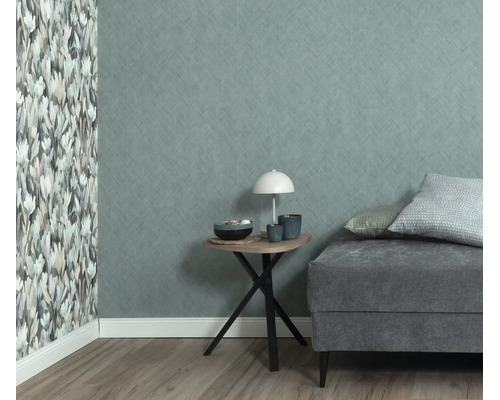 Woonkamer met vliesbehang, een muur met bloemenpatroon en een muur met textieloptiek, naast een bijzettafel en een gestoffeerde bank.