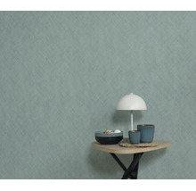 Gestructureerd behang met visgraatmotief op een muur, met daarvoor een bijzettafel met een lamp en decoratieve kommen.