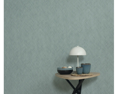 Gestructureerd behang met visgraatmotief op een muur, met daarvoor een bijzettafel met een lamp en decoratieve kommen.