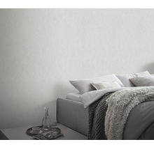 Een slaapkamer met gestructureerd behang in een neutrale look en een bed met kussens en een deken in een moderne stijl