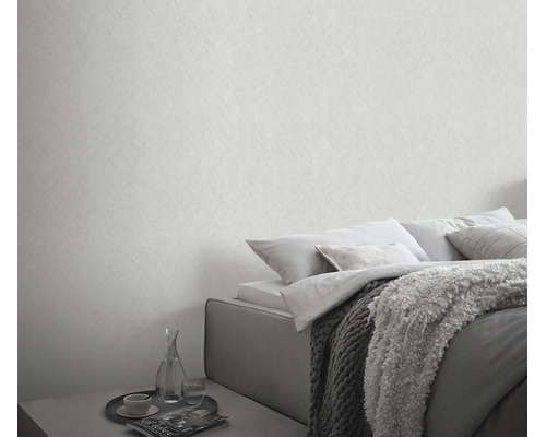 Een slaapkamer met gestructureerd behang in een neutrale look en een bed met kussens en een deken in een moderne stijl