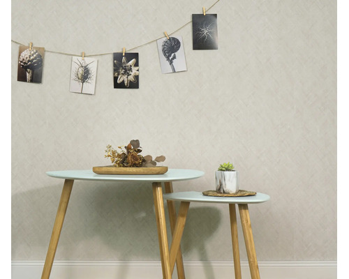 Woonruimte met gestructureerd behang, twee bijzettafels met houten poten en een fotolijn met botanische zwart-wit motieven aan de muur.