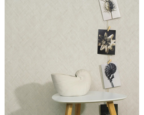 Behang met textuur en textielpatroon in een woonomgeving met een bijzettafel, een vaas in de vorm van een nautilus en hangende ansichtkaarten.