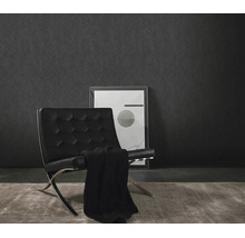 Moderne wandafwerking met gestructureerd vliesbehang voor een minimalistische fauteuil en een ingelijst kunstwerk.