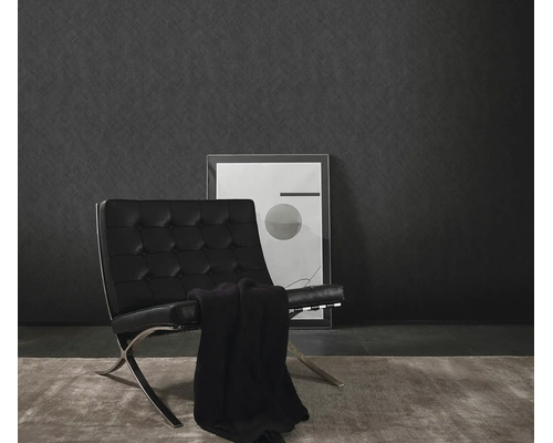 Moderne wandafwerking met gestructureerd vliesbehang voor een minimalistische fauteuil en een ingelijst kunstwerk.