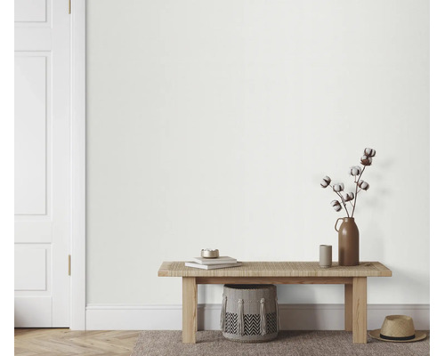 Lichte muur in een modern ingerichte hal met een houten bank, katoentakken in een vaas en een gevlochten mand.