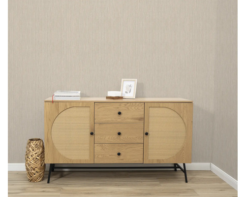 Houten dressoir met rotan vlechtwerk fronten, drie lades en twee deuren op een zwart metalen onderstel in een modern ingerichte kamer.