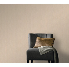Vliesbehang met subtiele textuur in een woonkamer met een gestoffeerde fauteuil en kussens