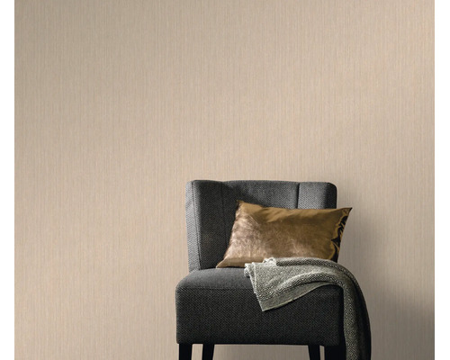 Vliesbehang met subtiele textuur in een woonkamer met een gestoffeerde fauteuil en kussens
