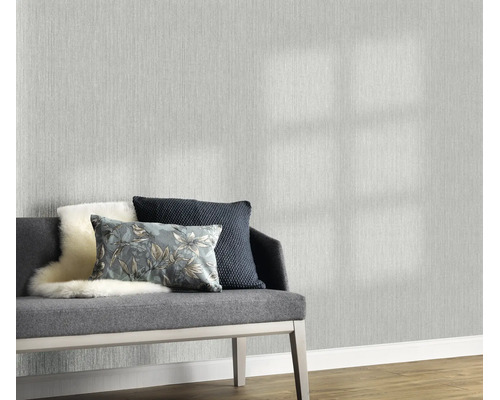 Vliesbehang met een fijne textielstructuur in een woonkamer met een gestoffeerd bankje en decoratieve kussens voor de behangen wand.