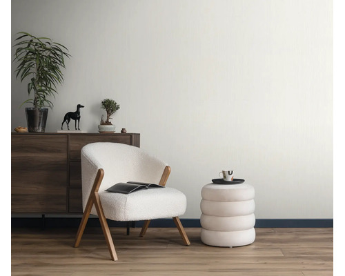 Woonkamer met moderne fauteuil in bouclé look, ronde poef, houten dressoir en kamerplant in een lichte en huiselijke omgeving.