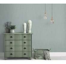 Woonkamer met gestructureerd vliesbehang, ladekast, decoratieve beelden en hanglampen in een klassieke interieurstijl.