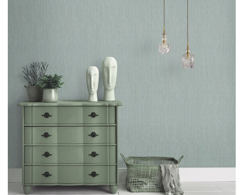 Woonkamer met gestructureerd vliesbehang, ladekast, decoratieve beelden en hanglampen in een klassieke interieurstijl.