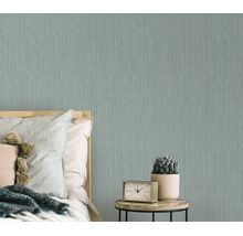 Moderne vliesbehang met subtiele textuur in een slaapkamer met nachtkastje en klok