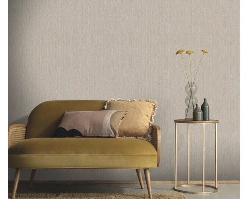 Woonkamer met effen vliesbehang met textielstructuur, een bank met kussens en een bijzettafel met glazen vaas in een modern interieur.