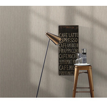 Gestructureerd vliesbehang in een moderne woonkamer met vloerlamp, barkruk en koffiebord.